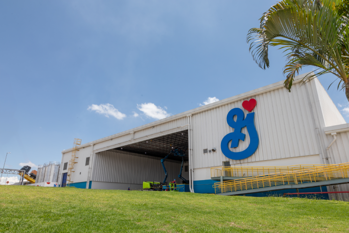 Industrial building with large General Mills logo on the exterior, surrounded by greenery showcasing its identity and purpose. The sky is clear with few clouds
