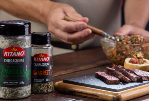 Three Yoki Brand Caseríssima seasoning packs with bowls of seasoned noodles, vegetables, and spices in front, against a wooden backdrop.